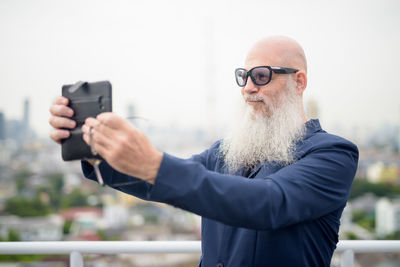 Portrait of man holding camera while standing outdoors