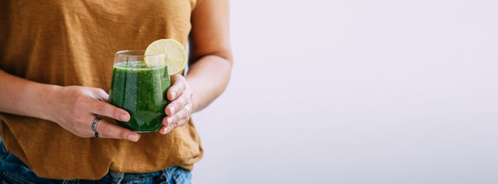 Midsection of woman holding plant against white background