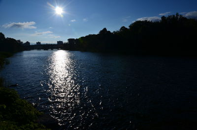 Scenic view of river by silhouette trees against sky
