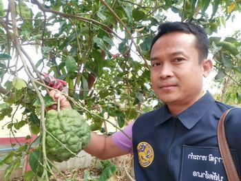 Portrait of man holding food against trees