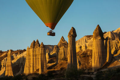 Low angle view of hot air balloon flying over rock formations