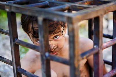 Portrait of woman looking through metal grate