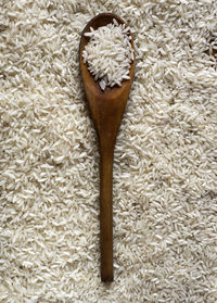 High angle view of wooden spoon on rice grain