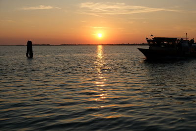 Silhouette boat in sea against sky during sunset