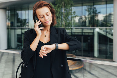 Portrait of young businesswoman standing against wall