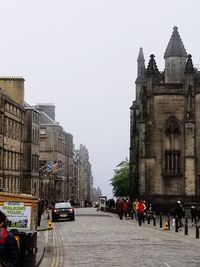 People on city street amidst buildings against clear sky