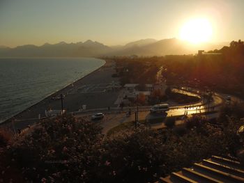 High angle view of city by sea against sky during sunset