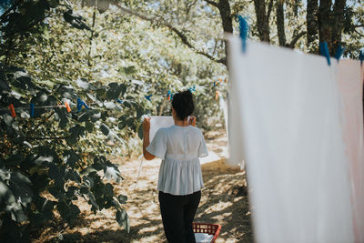 Rear view of woman standing by tree