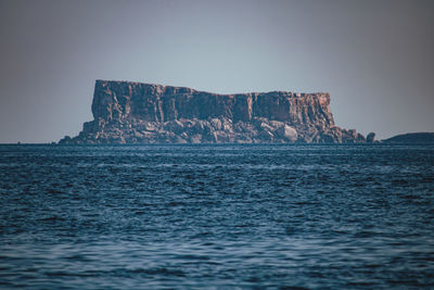 View of rock formations in sea against sky