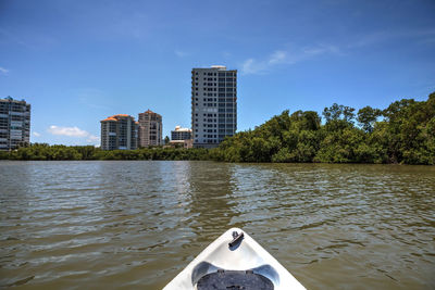 Boat in river by city against sky