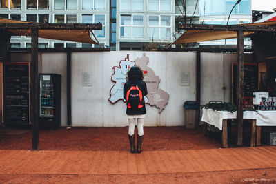 Rear view of woman standing against map on wall