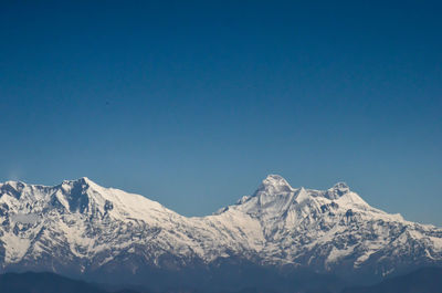 Scenic view of snowcapped mountains against clear blue sky