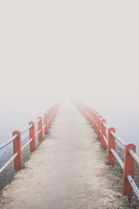 View of wooden walkway by sea against sky