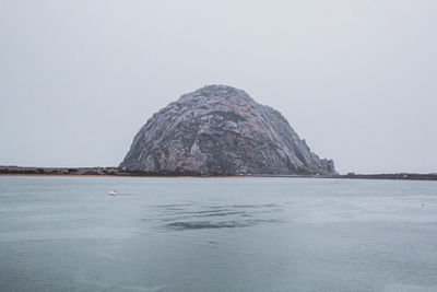 Rock formation in sea against clear sky