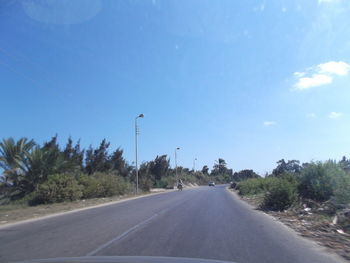 Road amidst trees against sky seen through car windshield