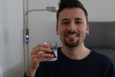 Portrait of smiling young man drinking glass