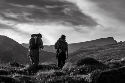 Rear view of men on mountain against sky