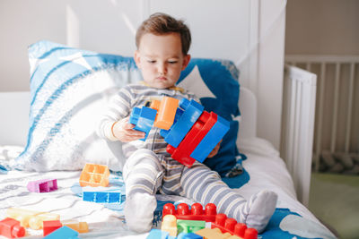 Boy holding toy on bed at home