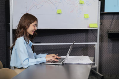 Businesswoman using laptop while sitting on table