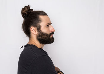 Portrait of young man looking away against white background