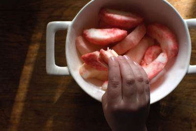 High angle view of hand holding bowl on table