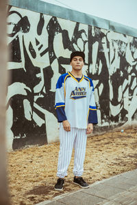 Portrait of smiling young man standing against graffiti wall