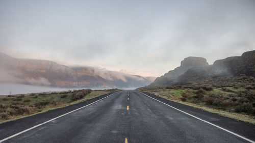 Road leading towards mountains against sky