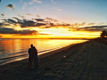 Rear view of silhouette man standing on beach at sunset