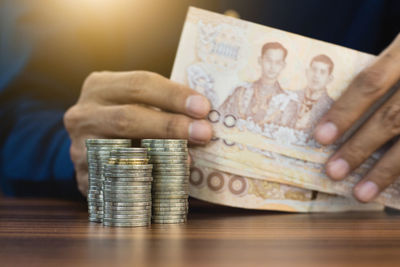 Human hand holding a stack of coins on table