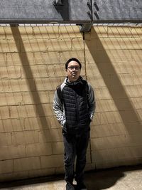 Portrait of young man standing against wall