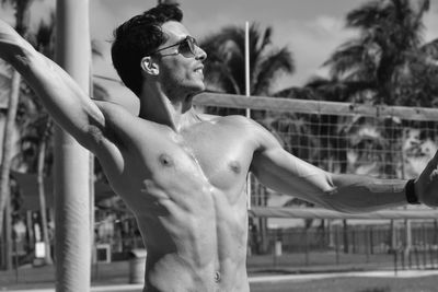 Muscular man with arms raised standing at beach