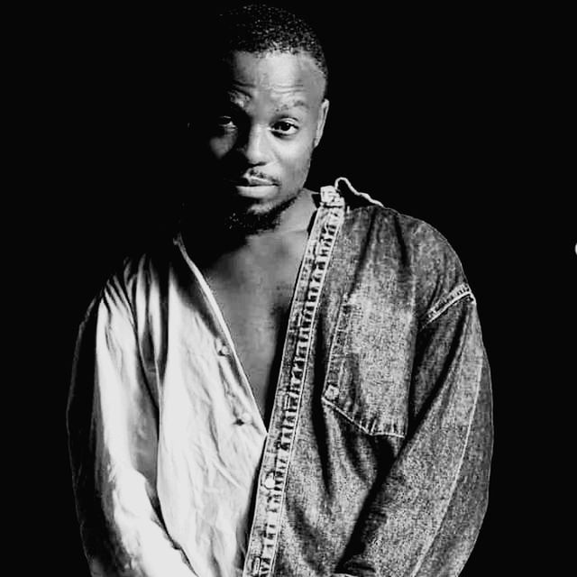 one person, black and white, portrait, black background, front view, studio shot, monochrome photography, adult, waist up, indoors, young adult, looking at camera, monochrome, casual clothing, person, black, serious, lifestyles, standing, looking, men, clothing