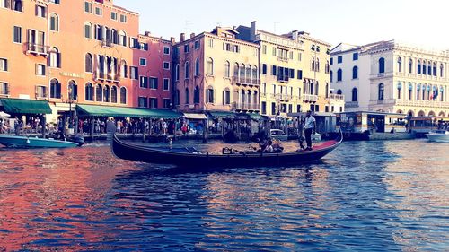 Boats in canal amidst buildings in city