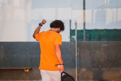 Rear view of young man standing against wall