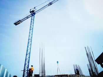 Low angle view of crane against clear blue sky