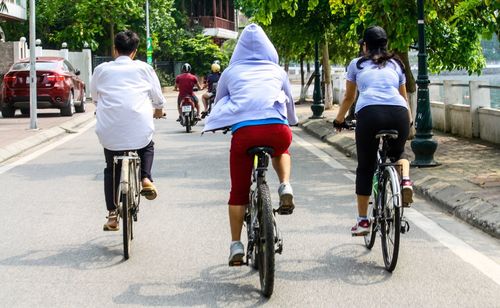 Rear view of people riding bicycle