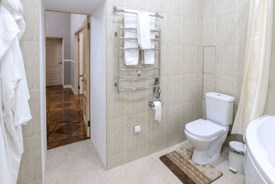 Bathroom with white sink and toilet. white bathrobes for guests hang on wall.