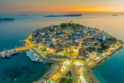 High angle view of townscape by sea against sky during sunset