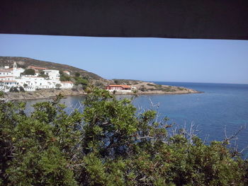 Scenic view of sea by buildings against clear blue sky