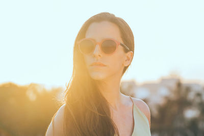 Portrait of young woman wearing sunglasses against sky