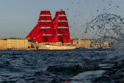 Red boat sailing in sea against sky