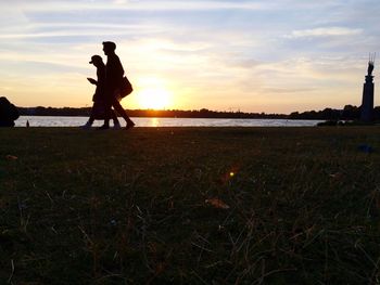 Silhouette of woman on field at sunset
