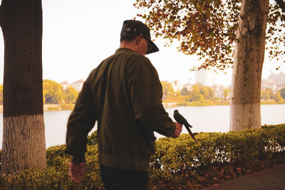 Rear view of man standing by tree against sky