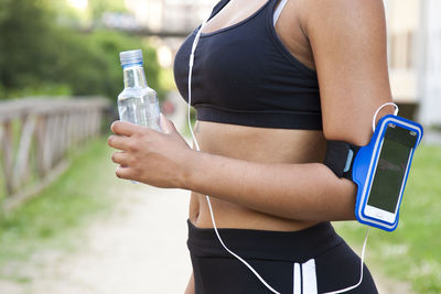 Midsection of runner woman holding bottle 