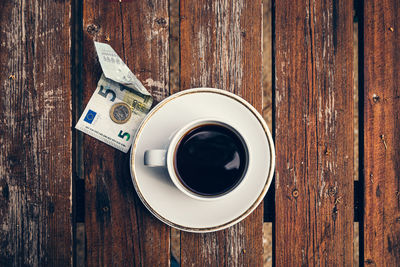 Directly above shot of coffee on table with banknote and currency