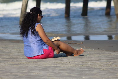 Side view of woman sitting on beach