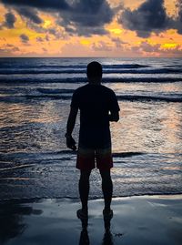 Silhouette man standing on beach against sky during sunset