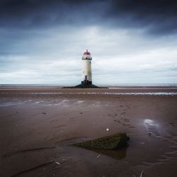 Lighthouse by sea against sky