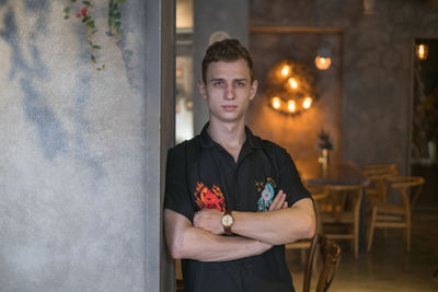 Portrait of young man standing by wall