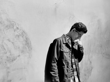 Young man standing by wall